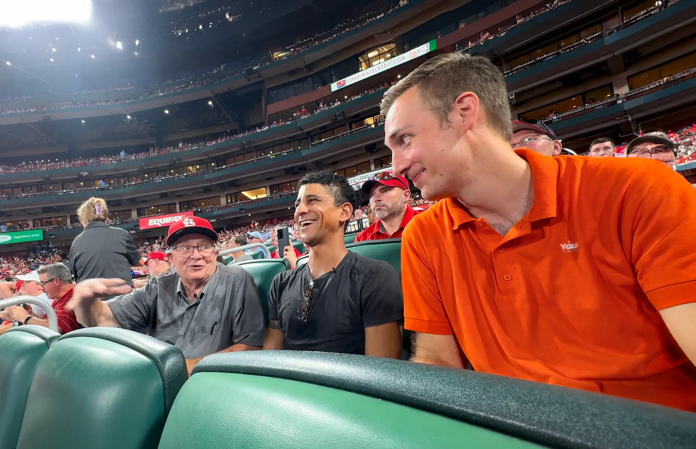 Jared Young, in an orange shirt, joins John and Julian in their seats at Busch Stadium
