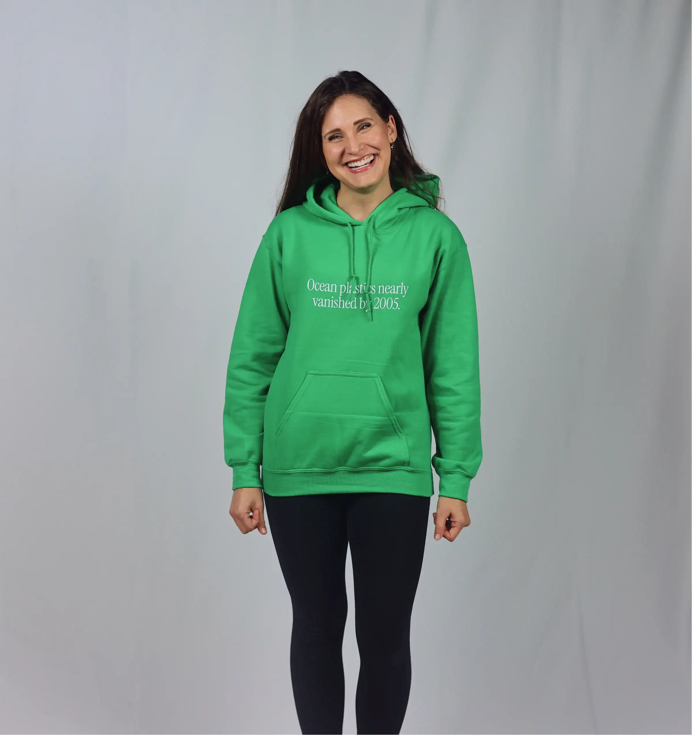 A woman in a green hoodie printed with “Ocean plastics nearly vanished by 2005”